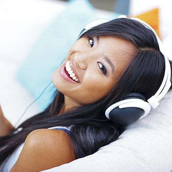 A young woman with white teeth smiling while listening to music