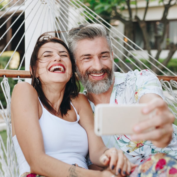 A couple relaxing on a hammock and smiling