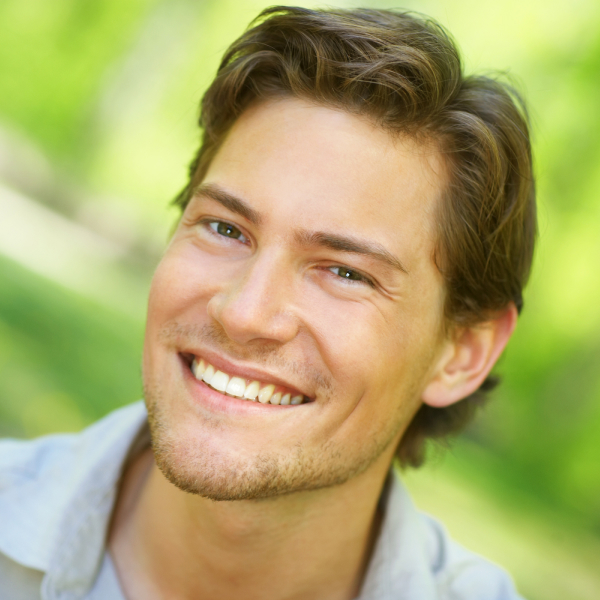 A young man smiles after receiving teeth whitening at Dale City Smiles